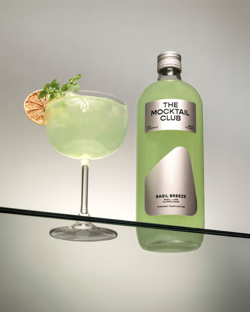 Bottle with Basil Breeze mocktail 99cl and mocktail glass filled with the Basil Breeze mocktail