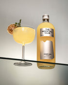 Bottle with Ginger Gem mocktail 99cl and a glass filled with Ginger Gem mocktail