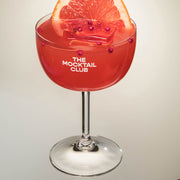 Mocktail glass filled with ice cubes, Grapefruit Grace mocktails and finished with pink pepper and a slice of grapefruit
