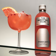 Bottle with Grapefruit Grace mocktail 49cl and a glass filled with the Grapefruit Grace mocktail