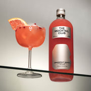 Bottle with Grapefruit Grace mocktail 99cl and mocktail glass filled with the Grapefruit Grace mocktail