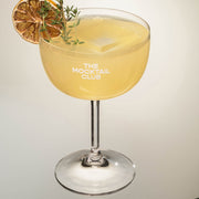 Mocktail Glass filled with ice cubes, Ginger Gem mocktail, finished with thyme and a slice of dried lime 