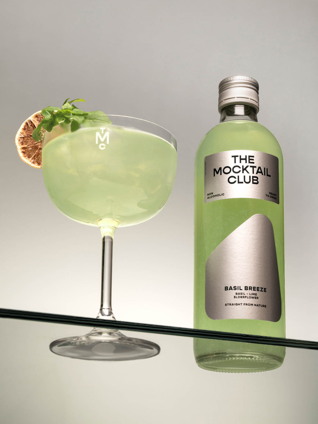 Bottle with Basil Breeze mocktail 49cl and mocktail glass filled with Basil Breeze mocktail