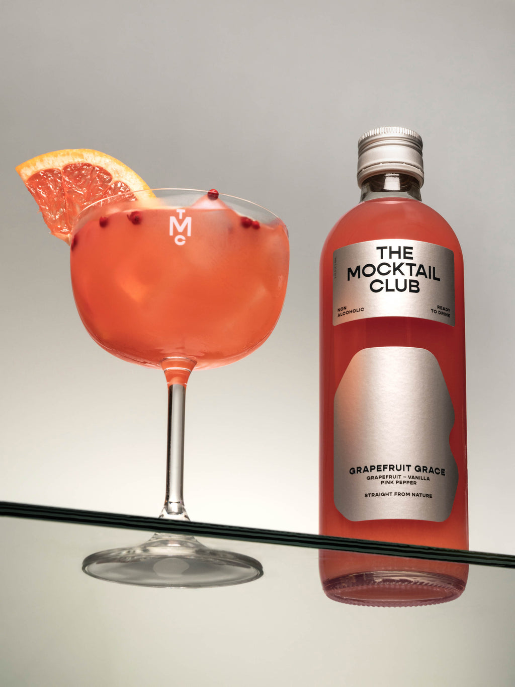 Bottle with Grapefruit Grace mocktail 49cl and a glass filled with the Grapefruit Grace mocktail 