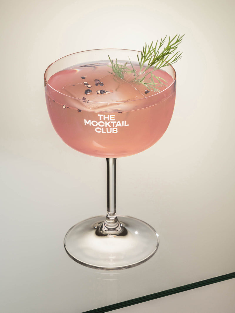 Mocktail glass filled with icecubes, Rhubarb Rush mocktail, finished with dill and timut pepper