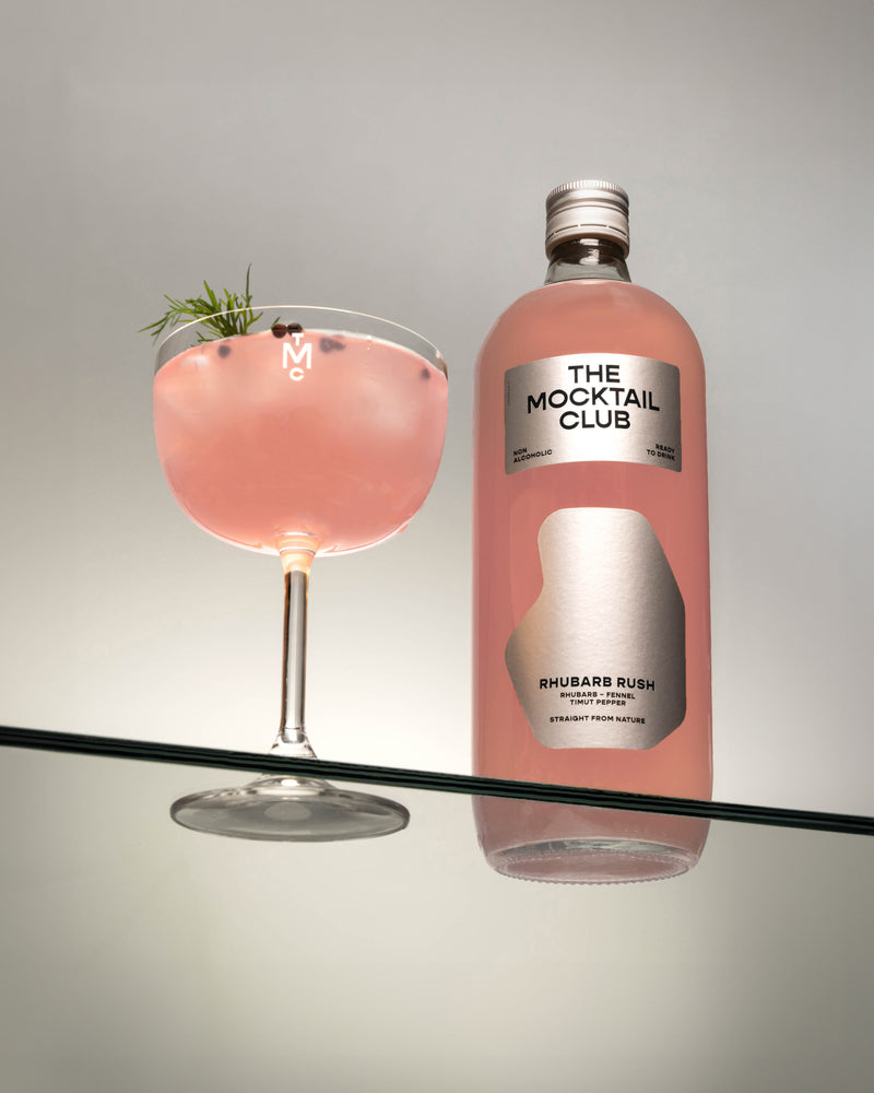 Bottle with Rhubarb Rush 99cl and glass filled with ice cubes, Rhubarb Rush mocktail, finished with dill and timut pepper